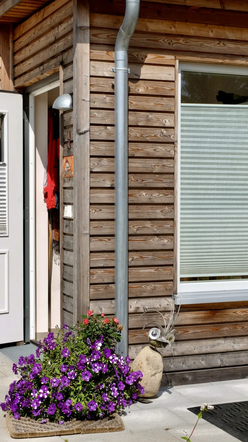 Detailaufnahme einer modernen Holzfassade mit Naturholz und Blumenschmuck – hochwertiger, nachhaltiger Holzrahmenbau.