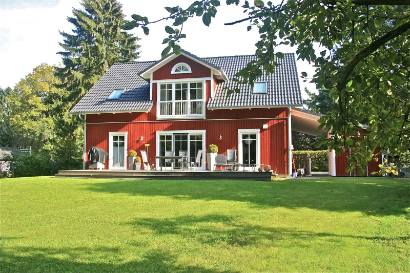 Detailaufnahme der stilvollen Holzfassade im traditionellen Schwedenhaus-Stil mit liebevollen Akzenten und moderner Farbgestaltung.