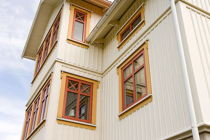 Helle Holzfassade mit rotbraunen Sprossenfenstern im typischen Stil eines schwedischen Holzhauses.