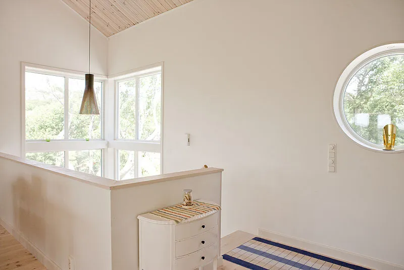 Heller Flur mit großem Fenster und Rundfenster in einem modernen skandinavischen Holzhaus.